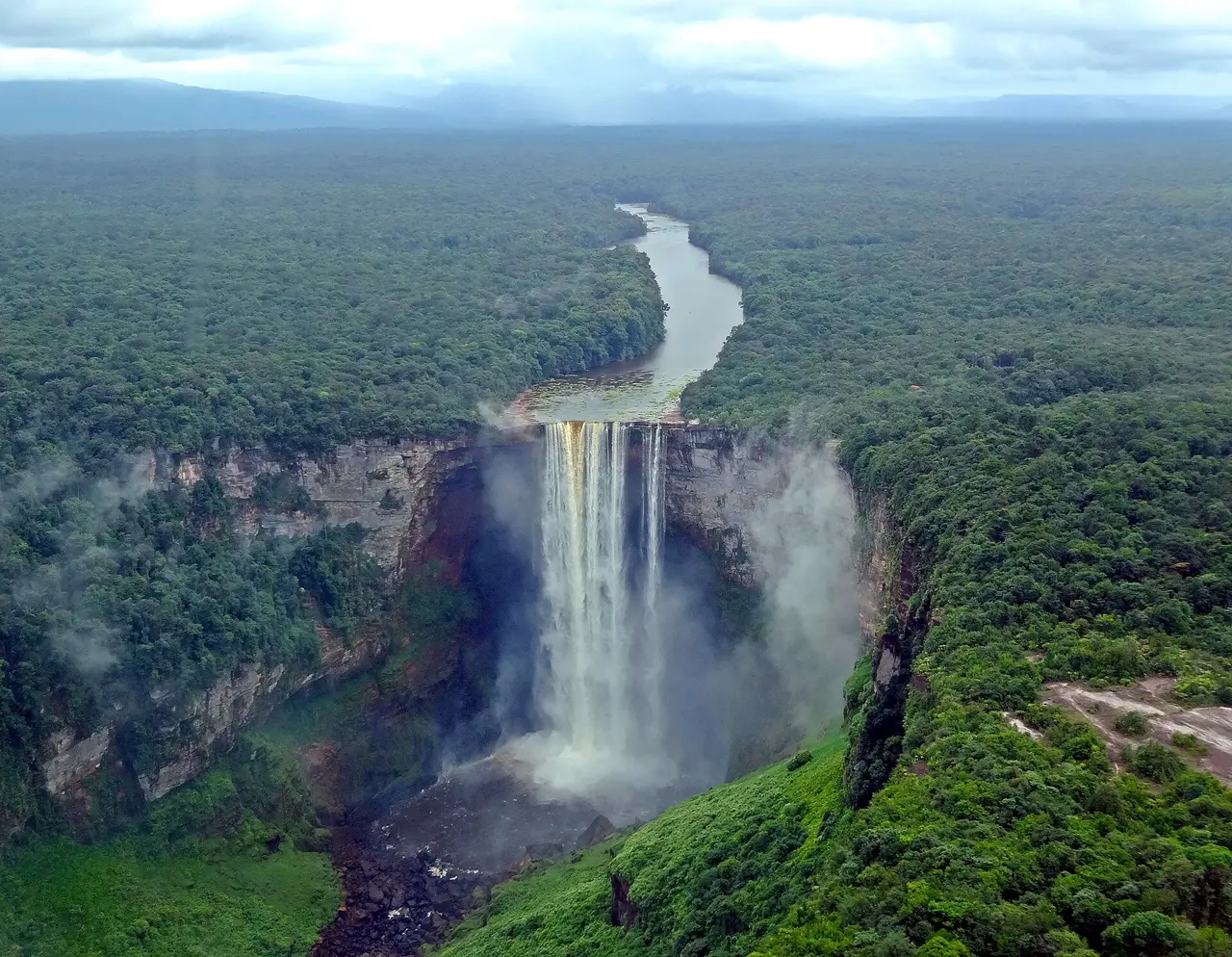 Aerial view of Kaieteur Falls with the river winding away through unbroken rainforest