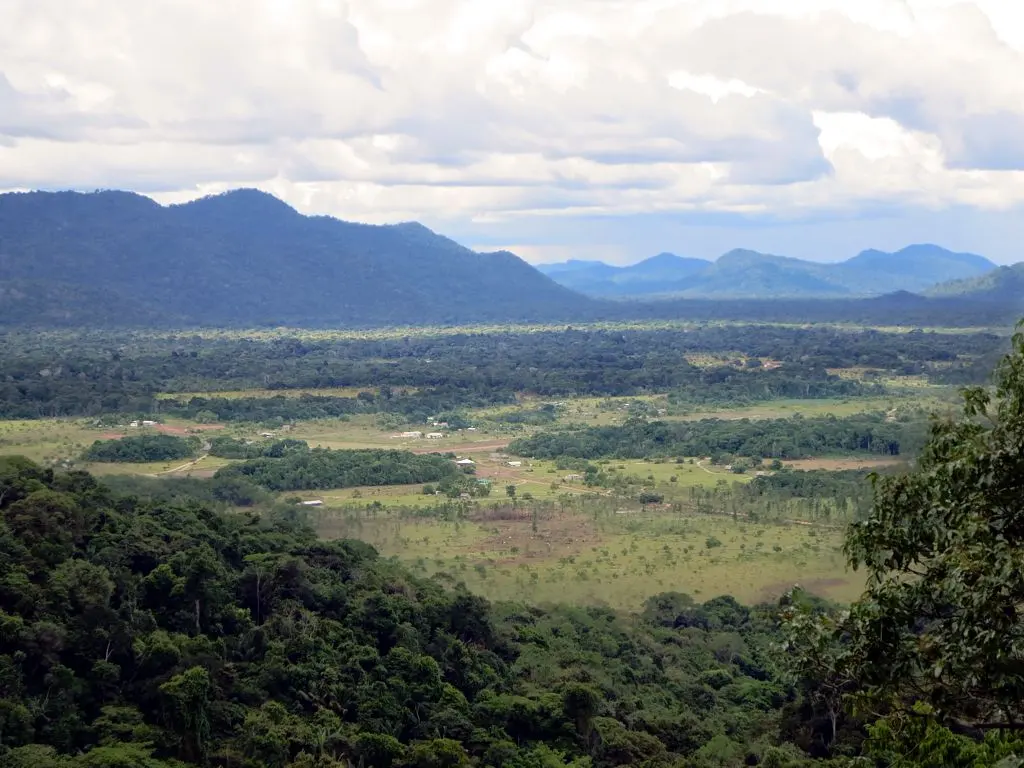 View from Surama Mountain over the village clearing, savannah and forest towards distant ranges